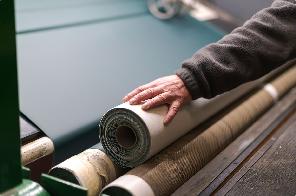 person with hand on a roll of fabric